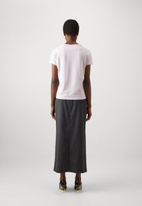 Ljusrosa kortärmad skjorta i kombination med en lång, mörkgrå kjol. Svarta högklackade skor med ljusgröna accenter. Enkelt, skräddarsytt design.