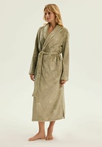 Oliwkowy szlafrok z długimi rękawami, zapinany na zawiązanie, z paskiem w talii. Posiada teksturowane wzory liści wytłoczone na miękkim, pluszowym materiale.