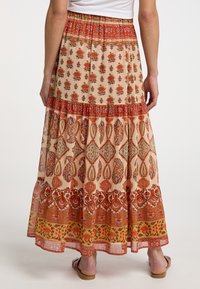 Maxi rok met een beige basis en intrigerende rode en oranje bloemenpatronen. Elastische tailleband, gelaagd ontwerp en gerimpelde zoom.