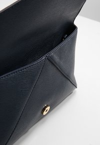 Granatowa kopertówka z ekoskóry w stylu koperty, z geometrycznym wzorem, złotym zatrzaskiem i fakturowaną powierzchnią.