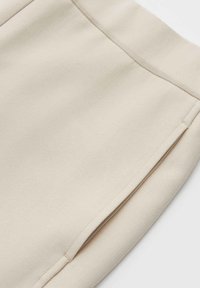 Beige figurbetonter Rock aus glattem Stoff, mit klaren Linien, minimalistischen Design und dezenten Nähten entlang der Nähte.