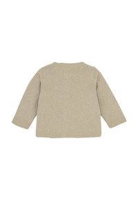 Beige långärmad stickad topp med rund halsringning, med en texturerad yta och rak nederkant. Bakifrån syns sömlös design.