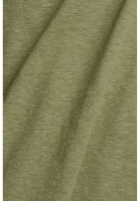 Gros plan d’un tissu tricoté doux de couleur vert olive clair montrant une texture fine et des plis subtils dans le matériau.