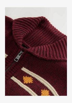 Burgundowy sweter robiony na drutach z wysokim kołnierzem, zdobiony kremowymi i pomarańczowymi wzorami oraz czarnym zamkiem błyskawicznym. Teksturowany materiał z prążkowanymi akcentami.