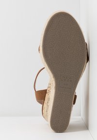 Bruine kurken sandaal met een gestructureerde rubberen zool, met een tan synthetisch bovenwerk en een verstelbare enkelband.