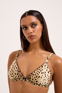 Trīsstūra formas bikini augšdaļa krēmkrāsā ar brūnu leopardu plankumu rakstu. Funkcijas ruffled malās, regulējamas siksnas un centrālais dekoratīvais bloķējošs elements.