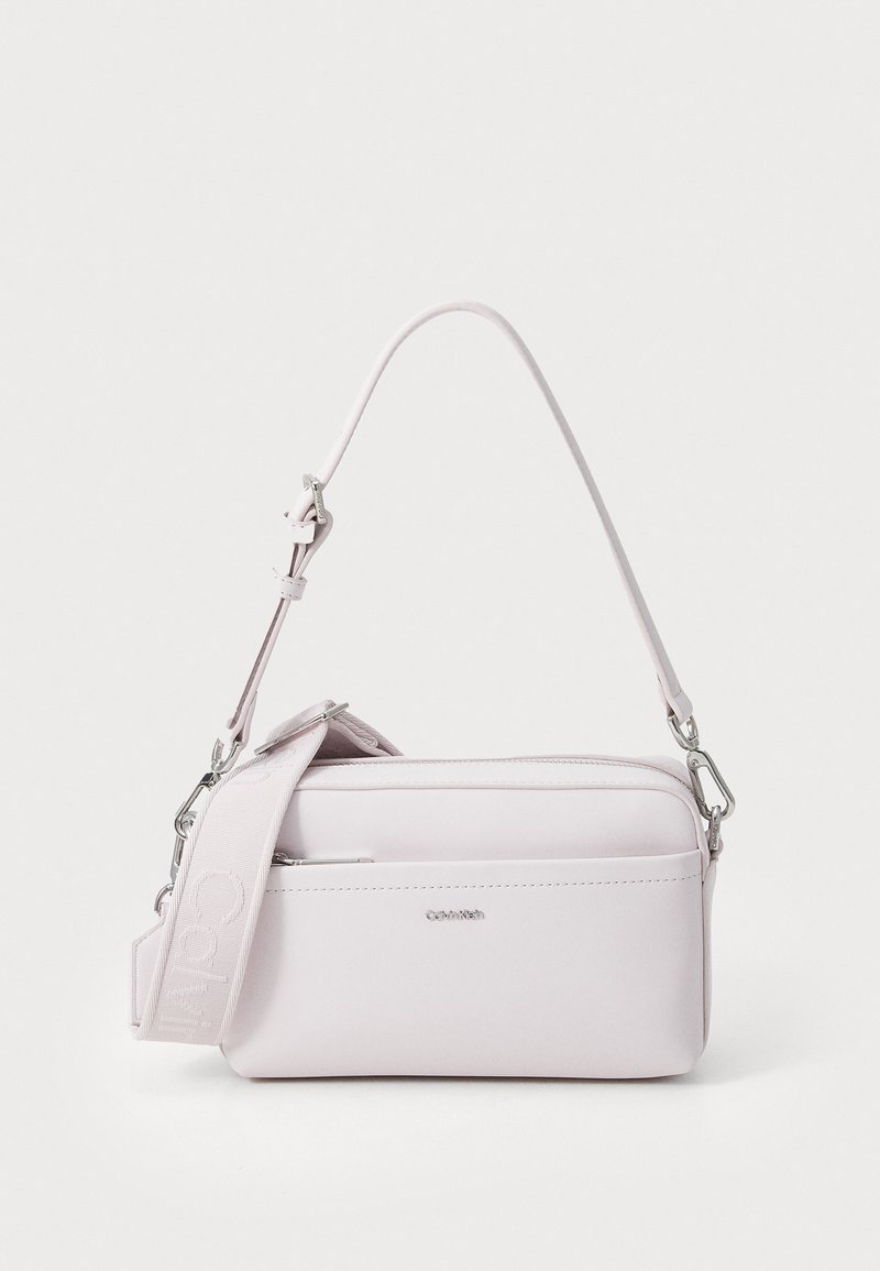 Ljusrosa crossbody-väska i mjuk läder. Har en rektangulär form, dragkedjefack och ett avtagbart tygband med logotyp.