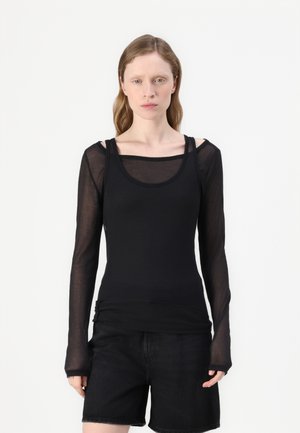 Zwarte langwerpige top van doorzichtig materiaal met een ronde hals. Kenmerkend zijn het gelaagde ontwerp en de aansluitende silhouet, gecombineerd met zwarte shorts.