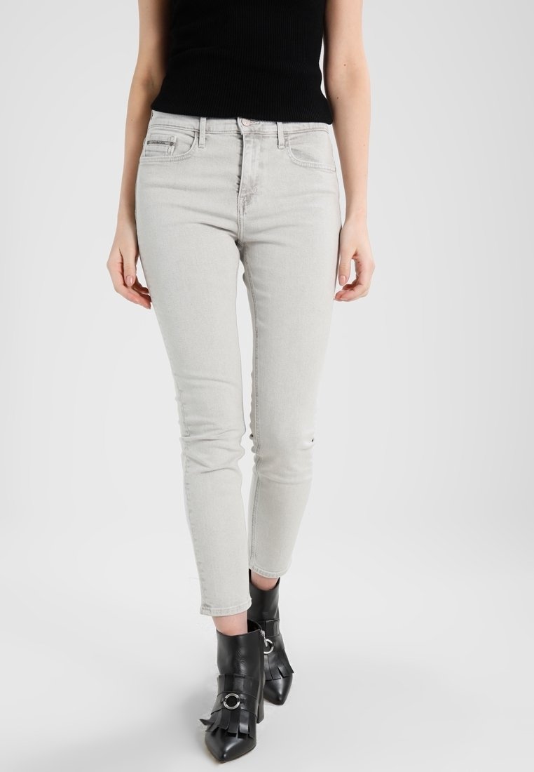 Ljust grå smala jeans med medelhög midja, slim fit och subtil slitdetalj vid knäna. Matchas med svarta ankellånga stövlar.