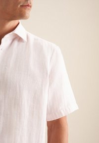 Camicia rosa chiaro a maniche corte in un tessuto testurizzato con colletto e pattina con bottoni, caratterizzata da sottili righe per un tocco di dettaglio.