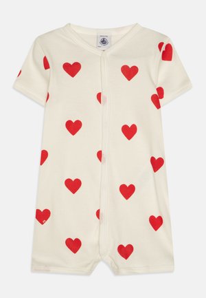 Lyhythihainen haalarimekko vaaleassa puuvillassa, jossa on punaisia sydänprinttejä. Mallissa on napitus edessä ja sopiva trimming.