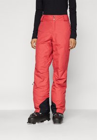 Pantalons de ski isolés rouges avec un accent noir aux chevilles, dotés d'une fermeture éclair et d'un bouton, et d'une coupe décontractée pour le confort et la mobilité.