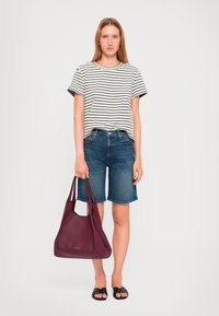 Gestreepte zwart-witte t-shirt, denim shorts, zwarte sandalen; houdt een gestructureerde bordeauxkleurige handtas vast met dubbele handvaten.
