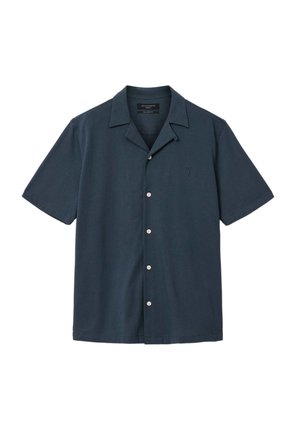 Chemise bleu foncé à manches courtes avec col campagnard, cinq boutons blancs, et logo brodé subtilement sur le côté gauche de la poitrine.