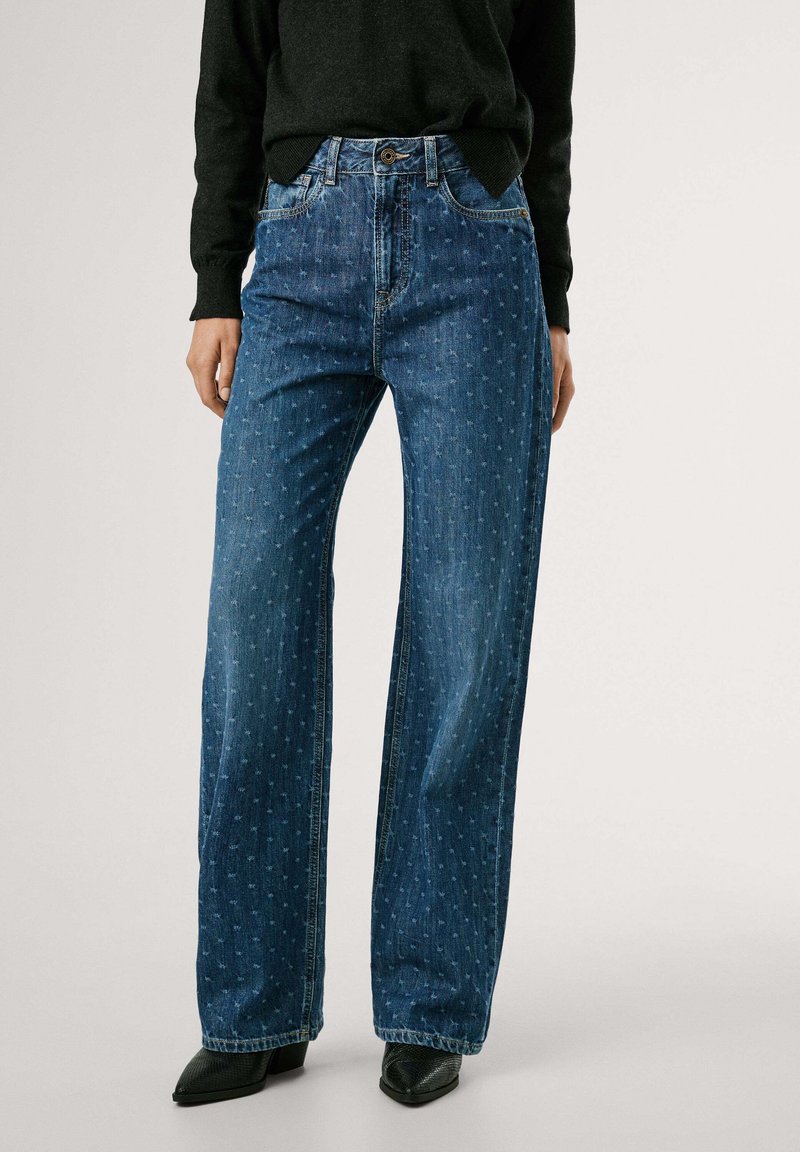 Jean large en denim bleu foncé avec une texture à motif subtil. Conception taille haute avec poches avant et fermeture à bouton.