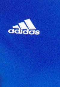 Blue fabric featuring a smooth texture, with a white embroidered Adidas logo and three stripe design in the top left corner.