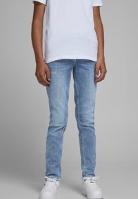 Slim fit džínové kalhoty ve světle modré barvě s vybledlým efektem, se pěti kapsami a prošitými detaily. Stylizované s bílým tričkem a teniskami.