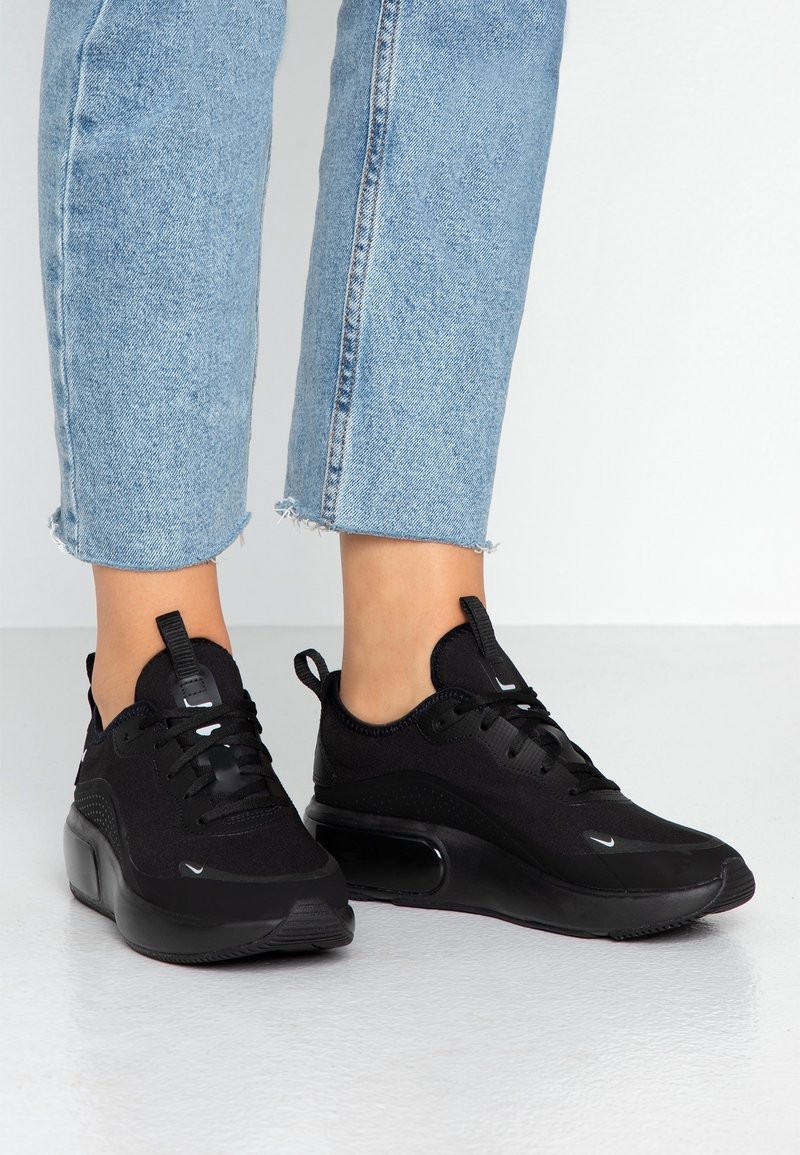 Scarpe sportive nere con tomaia in rete, chiusura con lacci e colletto imbottito. Presentano una suola a contrasto e un marchio discreto sul lato.