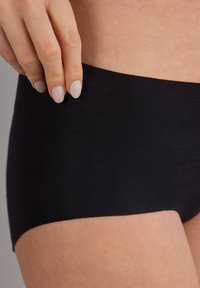 Černé bezešvé šortky na mladé chlapce, vyrobené z elastické tkaniny, mají hladký povrch a široký pas pro pohodlí a zakrytí.