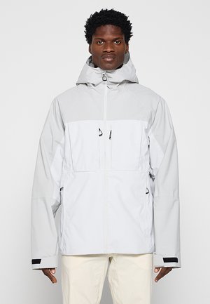 Jasnoszara wodoodporna kurtka z kapturem, z dwoma zamykanymi na zamek kieszeniami na piersi, regulowanymi mankietami i bezszwowym wykończeniem dla większej elastyczności.