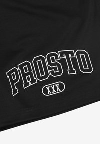 Czarna siateczkowa tkanina z odważnym białym napisem "PROSTO" i "XXX", z zakrzywionym banerem wokół tekstu, tworzy sportowy design.