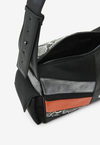 Sac à main noir texturé avec fermeture éclair, comportant un mélange de matériaux incluant un imprimé reptile, des accents argentés et orange. Sangle réglable incluse.
