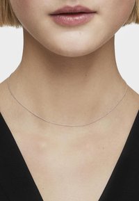 Collana sottile in argento che poggia sulla pelle nuda, caratterizzata da un design delicato con perline rotonde, minimalista e leggera.