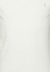 Vit bomull t-shirt med v-ringning och en mjuk yta, med en liten broderad logotyp på vänster bröst. Enkel och klassisk design.