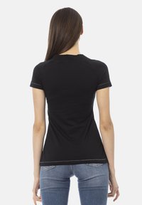 Zwarte katoenen t-shirt met korte mouwen, getailleerd ontwerp, gladde stof, zichtbare stiksels bij de mouwen en beneden aan de zoom.