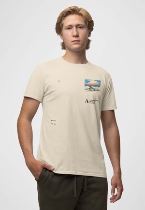 Beige bomulds t-shirt med et firkantet grafik af Mount Fuji, med trykte tekstdetaljer på brystet og venstre side. Korte ærmer, klassisk pasform.