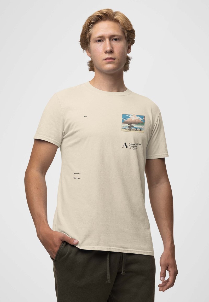 Beige bomulds t-shirt med et firkantet grafik af Mount Fuji, med trykte tekstdetaljer på brystet og venstre side. Korte ærmer, klassisk pasform.
