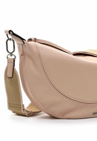 Růžová kožená taška přes rameno zaobleného tvaru, s texturovaným povrchem, kontrastním látkovým popruhem a stříbrnými kovovými prvky.