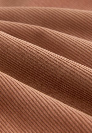 Textured, ribbed fabric in a warm terracotta color, showing multiple folds that enhance its depth and visual interest.
