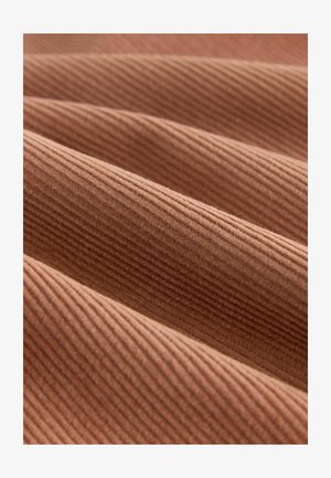 Textured, ribbed fabric in a warm terracotta color, showing multiple folds that enhance its depth and visual interest.