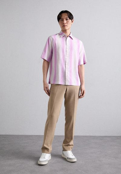 Kortermet skjorte med knapper i rosa og hvite striper, kombinert med beige bukser og hvite sneakers. Glatt stoff med en avslappet passform.