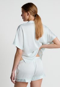 Ensemble de pyjama à manches courtes, vert clair, avec un haut à motifs, un dos ouvert et un short assorti doté d'une taille élastique et d'une bordure contrastante.