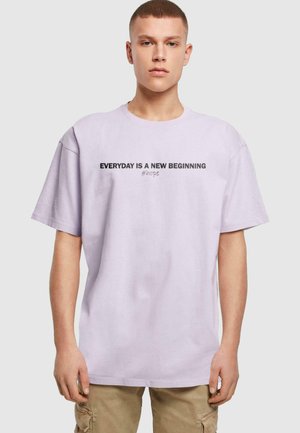 Hellblau-lila Baumwoll-T-Shirt mit kurzen Ärmeln und schwarzem Text: "JEDER TAG IST EIN NEUER BEGINN #Hoffnung" auf der Brust.