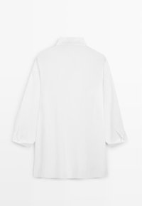 Chemise blanche à manches longues avec un col pointu, vue de dos, avec une coupe ample et des poignets boutonnés.