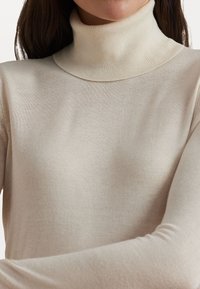Heledbeez turtleneck-sviiter pehmest ja elastses kangast. Omab keha järgivat siluetti ning soonikuga kaelust ja mansette.
