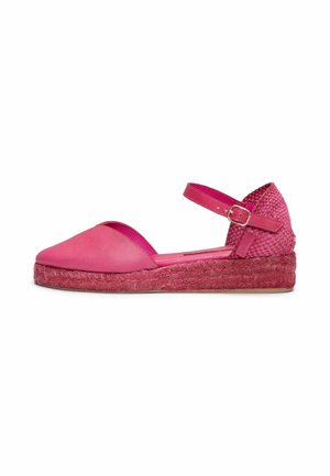 Espadrilla rosa de mujer con punta cerrada, correa en el tobillo con hebilla, tacón tejido y suela plana de yute sobre fondo blanco.