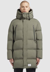Maslinasto zeleni puffer jakna s visokim ovratnikom, patentnim zatvaračem i teksturiranim završetkom. Ima podesivu kapuljaču s vezicama.