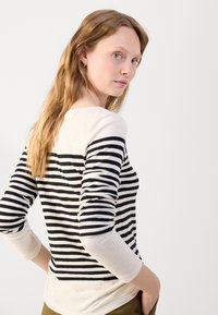 Svart og hvit stripete langermet topp med rund hals, kontrasterende ermer og en myk tekstur. Passformen virker avslappet med en lagdelt stil.
