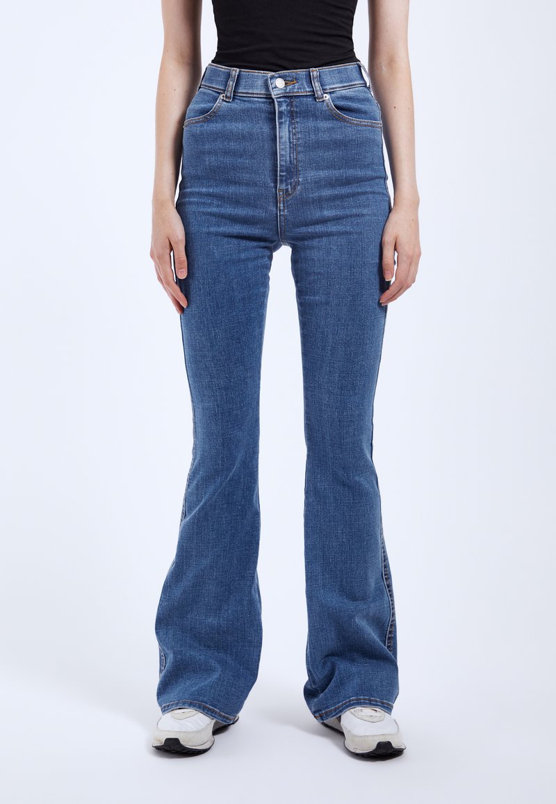 High-waisted, flared blue jeans made from denim. Features classic five-pocket design and subtle stitching details along the seams.