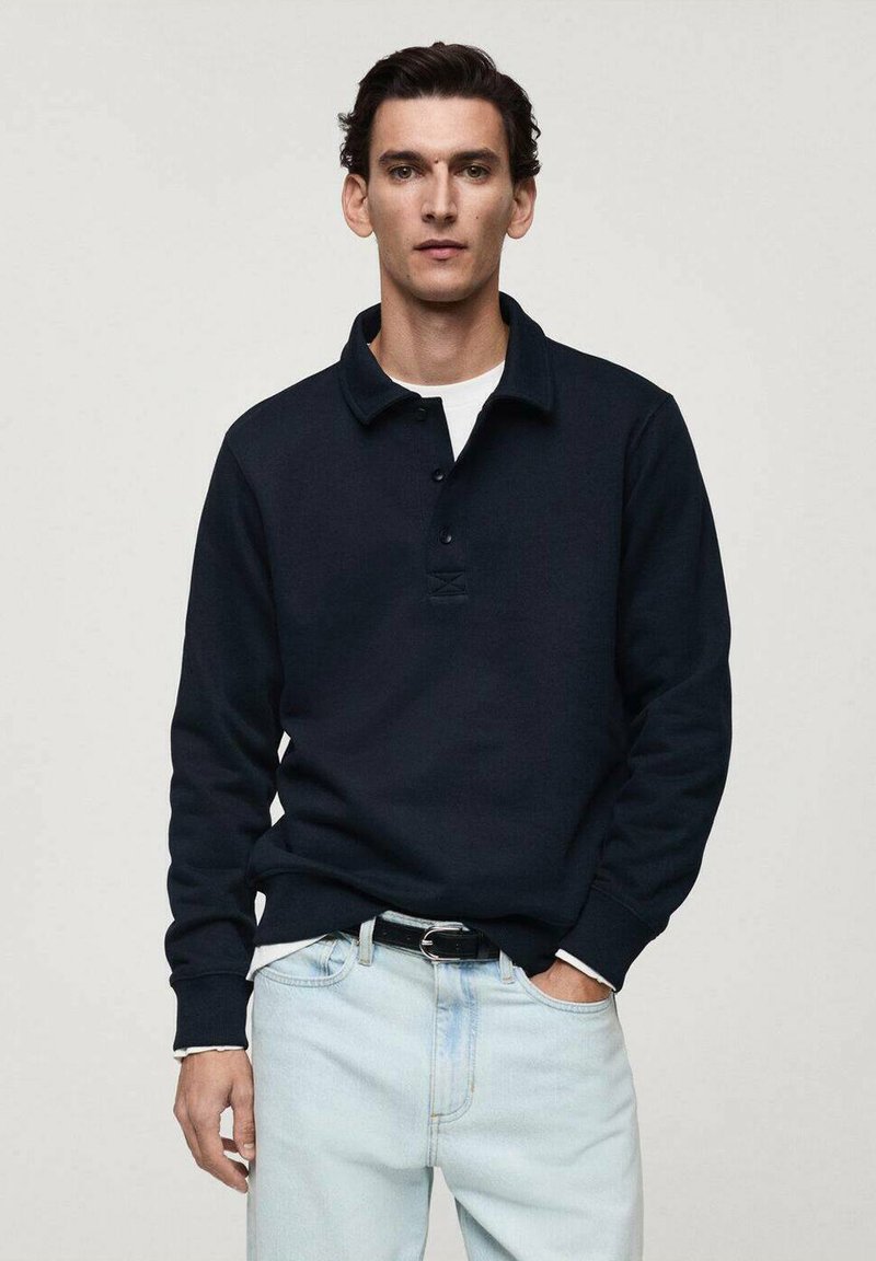Mörkblå långärmad polo med krage, tre knappslå och ribbade mudd, som är kombinerad med ljus tvättade jeans.