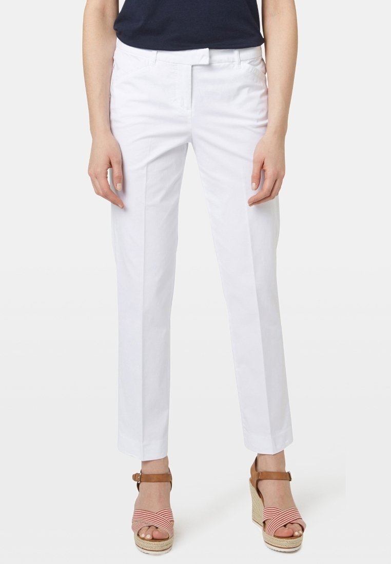 Witte op maat gemaakte broek met een rechte pijp, voorzien van een gladde textuur, riemlussen en voorzakken. Gepaard met gestreepte espadrille-sandalen.