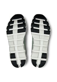 Schuhsohlen mit einem schwarzen Gummiprofil, das eine weiße Zwischensohle, strukturierte Segmente und geformte Details für bessere Griffigkeit aufweist.