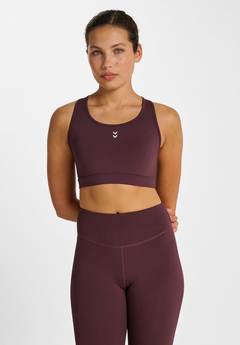 Bordeauxrode sportbeha met een ronde hals, brede bandjes en een aansluitend ontwerp. Heeft een klein logo in het midden en bijpassende leggings met hoge taille.