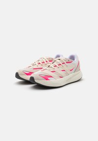Zapatillas deportivas beige y rosas con parte superior de malla, acentos rosas y suela de goma. Presentan cordones y un logotipo en tono sobre el costado.