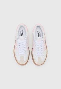 Adidas sneakers med en hvid syntetisk overdel med pink striber, beige ruskindsdetaljer og en gummisål. Klassisk snørebåndsdesign.