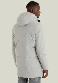 Ljusgrå puffjacka med huva, med horisontella quiltade sektioner och elastiska manschetter. Tillverkad av ett slätt, vattentåligt material.